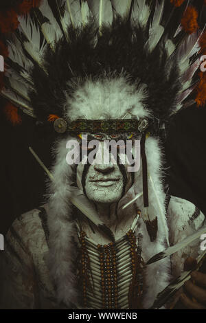 Costume aborigena, American Indian con pennacchio di piume, ax e dipinti di guerra Foto Stock