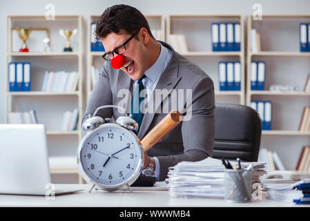 Imprenditore clown in ufficio con la mazza da baseball e un allarme c Foto Stock