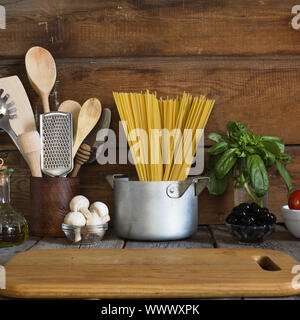 Spaghetti con gli ingredienti per cucinare la pasta su uno sfondo di legno, vista dall'alto. Concetto: cucina casalinga Foto Stock