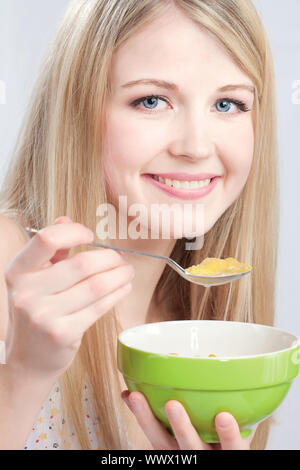 Sorrise donna cucchiaio di tenuta e la piastra, preparare da mangiare cornflex Foto Stock