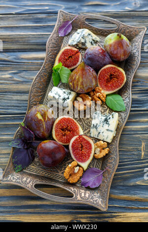 Fichi con formaggio blu e viola il basilico su un vassoio di bronzo Foto Stock