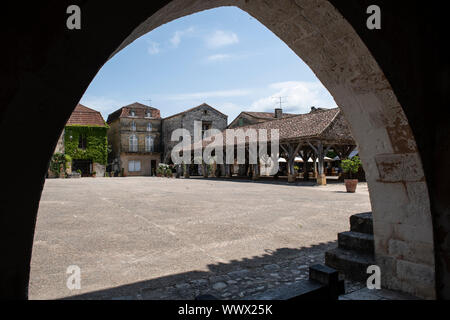 La piazza principale di Monpazier, osservata attraverso un arco Foto Stock