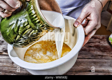 La cottura di alimenti. Donna cook versa il latte in una ciotola. Prodotti da forno. Foto Stock