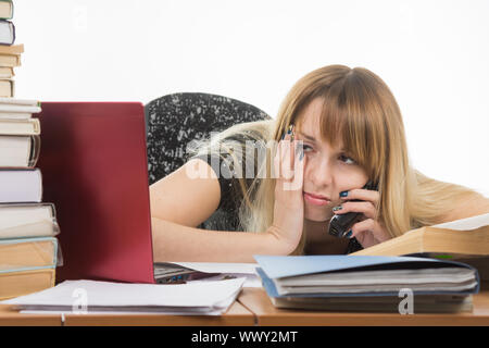 Stanco donna giovane lavoratore di ufficio a parlare al telefono e guardando il monitor Foto Stock