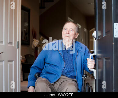 Anziani di 90 anni di vecchio uomo in sedia a rotelle al suo sportello anteriore, guardando verso il cielo Foto Stock