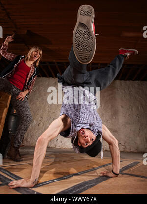 Giovane donna cheers sull'uomo facendo freestyle si erge a mano Foto Stock