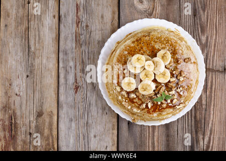 Frittelle di banane, noci e miele e foglia di menta, colazione in stile rustico, sullo sfondo di legno Foto Stock