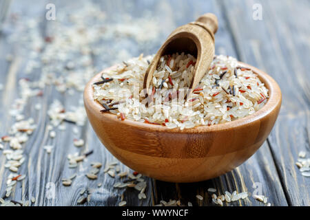 Cucchiaio di legno in un recipiente con una miscela di quattro tipi di riso. Foto Stock