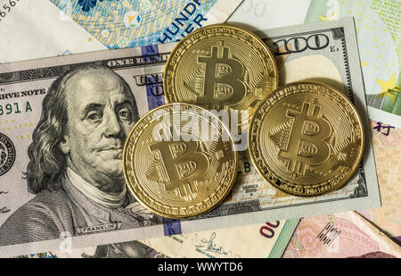Golden bitcoin su multi valuta banconote dollaro, yuan, euro Foto Stock