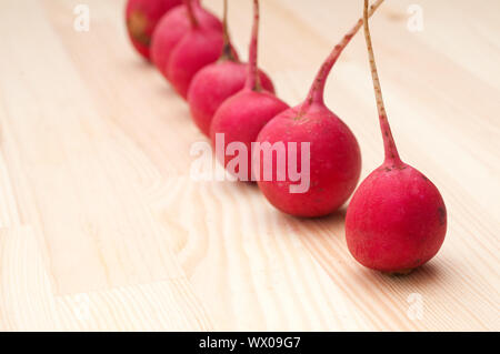 Rosso fresco raddish crudo su legno di pino tabella closeup Foto Stock