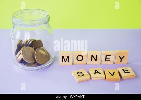 Il futuro della finanza, business banking e concetto finanziario. Flatlay centesimi di euro, un barattolo di vetro e lettere di cubi risparmiare denaro su due colore di sfondo. Foto Stock
