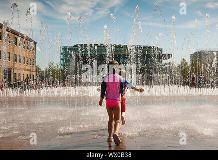 Bambini a giocare con le fontane in Granery Sq Kings Cross London REGNO UNITO Foto Stock