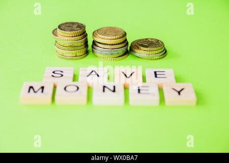 Il futuro della finanza, business banking e concetto finanziario. Flatlay centesimi di Euro e lettere di cubi di risparmiare sui costi di colore verde dello sfondo. Selective fo Foto Stock