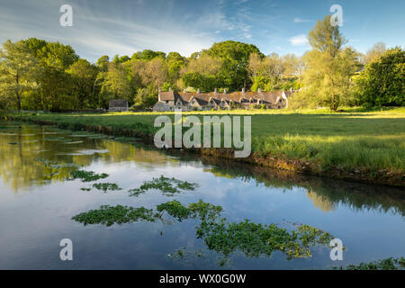 Arlington Row cottages attraverso il Fiume Coln in Cotswolds village di Bibury, Gloucestershire, England, Regno Unito, Europa Foto Stock