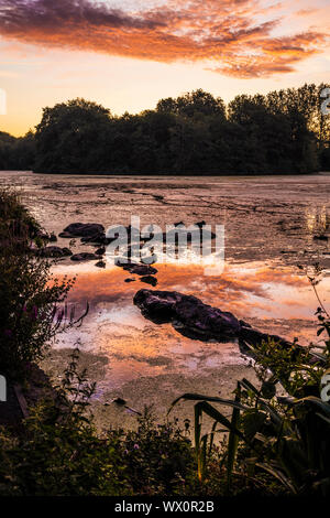 Tramonto su un piccolo lago noto come Liden Lagoon a Swindon, Wiltshire. Foto Stock