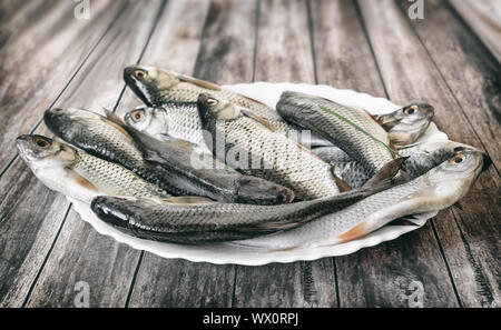 Pesce fresco sul tavolo su una piastra bianca. Foto Stock