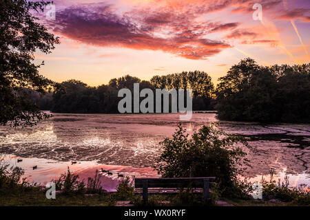 Tramonto su un piccolo lago noto come Liden Lagoon a Swindon, Wiltshire. Foto Stock