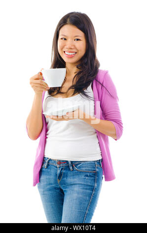 Un Cinese asiatica donna orientale con un meraviglioso sorriso toothy bere il tè o il caffè da una tazza bianca con piattino Foto Stock