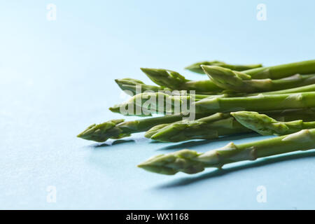 Un sano verde biologico gambi di asparagi pronto a cucinare su sfondo blu Foto Stock