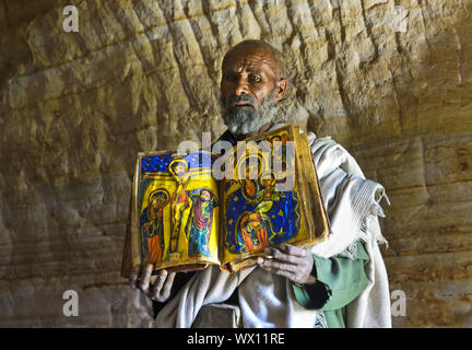 Un sacerdote ortodosso della Chiesa rock Mikael Mellehayzengi mostra libro liturgico, Tigray, Etiopia Foto Stock