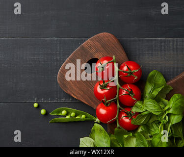 Succosa luminoso verdure estive al buio su un sfondo di legno, laici piatta Foto Stock