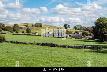 La frazione di Rowdale accoccolato sotto la sua collina e serbatoio di circolare nei pressi di Bakewell nel Derbyshire Peak District UK Foto Stock