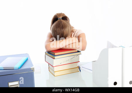 Donna giovane studente seduto alla sua scrivania addormentato su una pila di libri logorata da superlavoro e stress Foto Stock