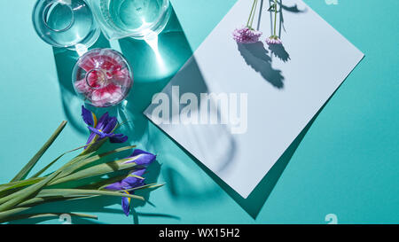 Un bouquet di fiori con vasi e un foglio di carta bianco su sfondo blu Foto Stock