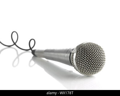 Un microfono dinamico con un cavo arrotolato su bianco. Foto Stock