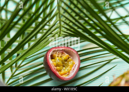 La passione di frutta tropicale e foglie di palmo su sfondo verde. Foto Stock