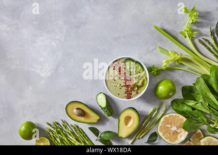 Fresche verdure biologiche e una piastra di frullati con semi di lino su un cemento grigio Sfondo con copia spazio. Vista superiore Foto Stock