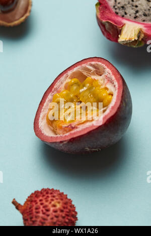 La metà dei frutti della passione con litchi e dragon frutto su uno sfondo blu Foto Stock