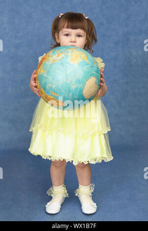 Bambina tenendo un globo di grandi dimensioni su uno sfondo blu Foto Stock