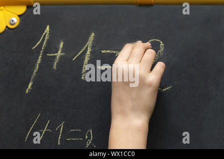 La ragazza scrive in gesso sulla lavagna. Foto Stock