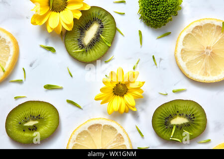 Modello di fiori di colore da giallo, verde fiori, fette di kiwi e limone. Close-up di sfondo a molla da ingredienti biologici. Foto Stock