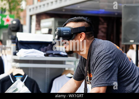 Un uomo che indossa la realtà virtuale gli occhiali e a cavallo di un simulatore di moto Foto Stock