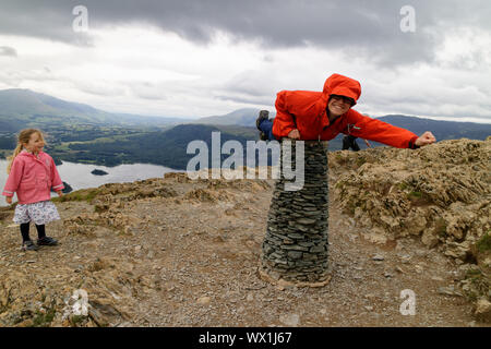 Una donna che finge di essere superman sul vertice del gatto campane nel distretto del lago mentre la figlia guarda su Foto Stock