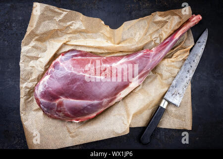 Raw gamba invecchiata di cervo con osso come vista dall'alto sulla carta marrone Foto Stock