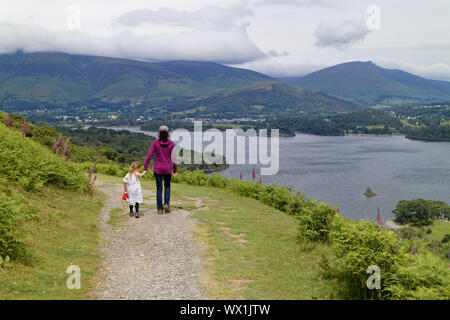 Madre e figlia camminando mano nella mano nel distretto del lago con Derwent Water al di là, Cumbria, Regno Unito Foto Stock