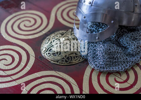 Viking casco con la catena posta su uno scudo rosso con forme d'oro di Sun, le armi per la guerra Foto Stock