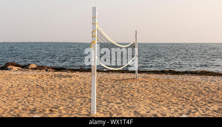 La spiaggia ha un campo di pallavolo net impostato sulla sabbia pronto per gli atleti di venire a giocare dall'acqua. Foto Stock