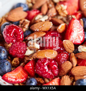 Organico naturale di lampone, fragola, mirtillo, dadi, avena e di lino miele sono una sana prima colazione dello sfondo. Foto Stock