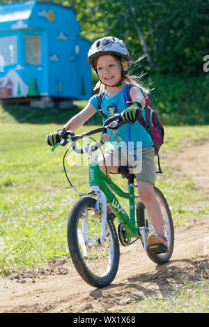 Una bambina di 5 anni) sorridendo come lui corre in suo bike Foto Stock