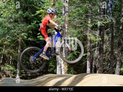 A sette anni di vecchio ragazzo facendo salta sulla sua mountain bike Foto Stock