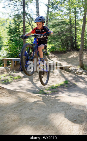 A sette anni di vecchio ragazzo facendo salta sulla sua mountain bike Foto Stock