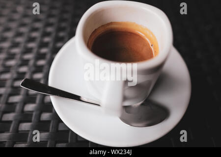 Dettagli con un bianco di ceramica tazza di caffè e un acciaio inossidabile cucchiaio in una tabella in un coffee shop Foto Stock