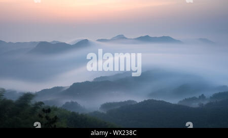 Mare di nuvole sopra le montagne all'alba Foto Stock