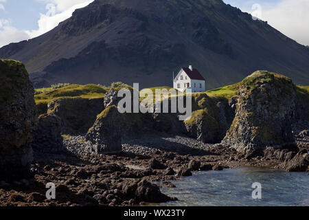 Casa sulla costa di basalto off Stapafell montagna, Arnarstapi, Snaefellsnes, Islanda, Europa Foto Stock