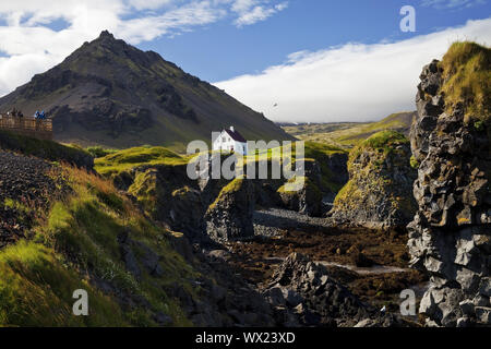 Casa sulla costa di basalto off Stapafell montagna, Arnarstapi, Snaefellsnes, Islanda, Europa Foto Stock