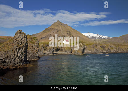 Casa sulla costa di basalto off Stapafell mountain e Snaefellsjoekull ghiacciaio, Arnarstapi, Islanda Foto Stock